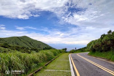 Road leading towards mountains against sky