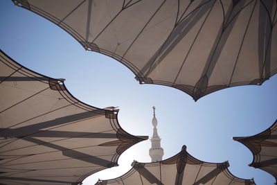Low angle view of umbrellas and tower against clear sky