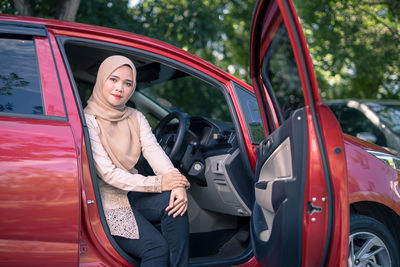 Beautiful woman standing on red car