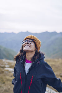 Carefree woman with eyes closed smiling while standing on mountain around ibones of anayet