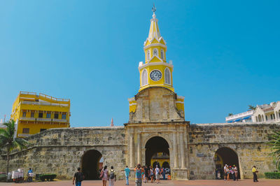 Tourists at historic church against clear blue sky