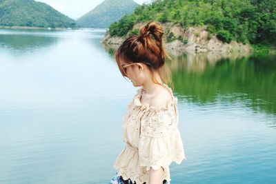 Side view of woman standing at lakeshore