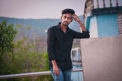 Portrait of young man standing against wall