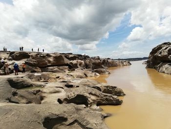 Scenic view of rocks on shore against sky