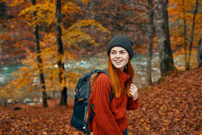 Portrait of smiling young woman in forest during autumn