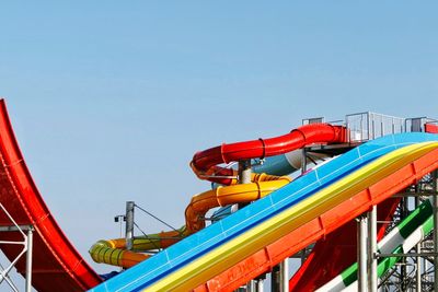 Low angle view of amusement park ride against clear blue sky