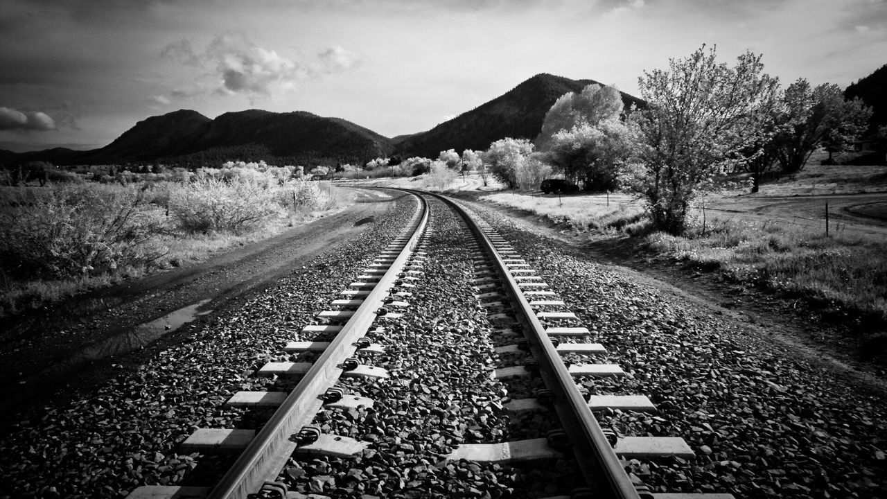 railroad track, rail transportation, the way forward, diminishing perspective, vanishing point, sky, tree, railway track, cloud - sky, landscape, nature, tranquility, tranquil scene, straight, day, outdoors, surface level, no people, mountain, long, cloud, growth, cloudy, non-urban scene, beauty in nature, scenics, non urban scene, remote