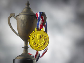 Close-up of rusty trophy and medal against sky