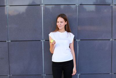 Portrait of young woman standing against wall