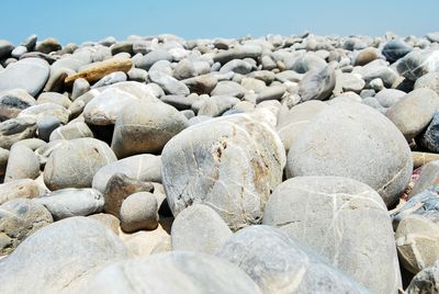 Pebbles at beach against clear sky