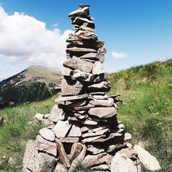 Stack of stones on field against sky