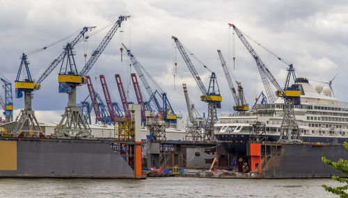 Cranes at commercial dock against sky