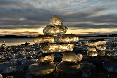 Stack of stones on beach against sky during sunset