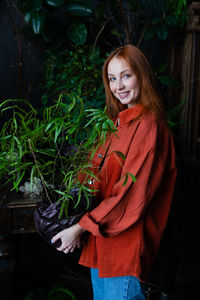 Portrait of young woman standing against plants