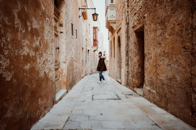 Portrait of young woman walking in alley