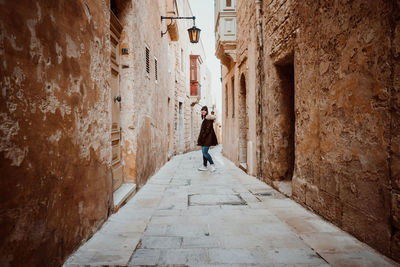 Man walking in alley amidst old building