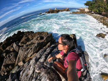 High angle view of woman sitting on rock by sea