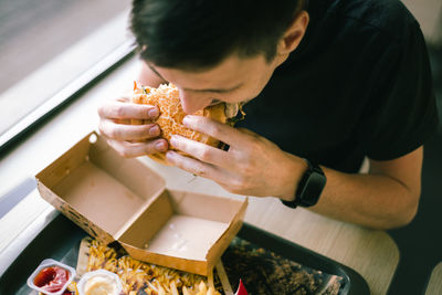 A young man eats fast food at a diner.