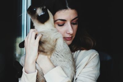 Beautiful young woman embracing cat