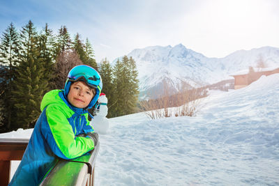 Portrait of smiling woman standing on snow covered mountain