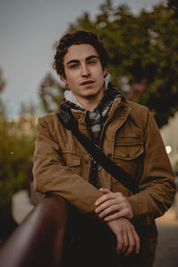 Portrait of young man standing by railing