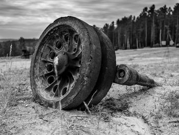 Close-up of old rusty wheel on field against sky