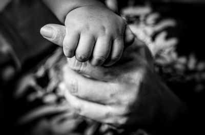 Close-up of man holding baby hands