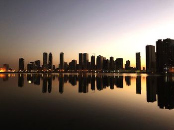 Reflection of buildings in lake against clear sky