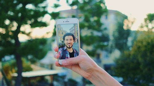 Midsection of woman photographing through smart phone outdoors