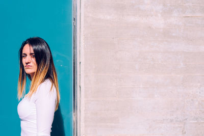 Portrait of woman standing against wall