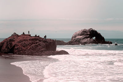 Rock formation on beach against sky