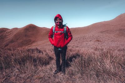 Portrait of man standing on red land against sky