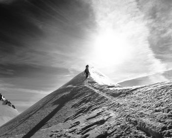 Low angle view of person on snow covered mountain against sky