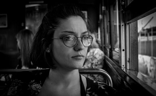 Close-up of thoughtful young woman looking through window in bus