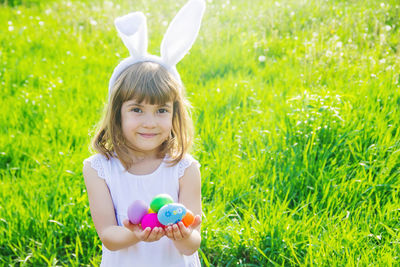 Portrait of cute girl playing with flowers on field