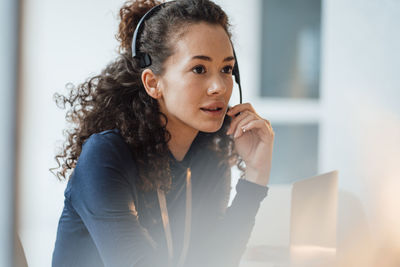 Customer service representative with curly hair talking through headset