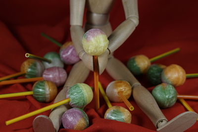 High angle view of figurine with colorful lollipops on red fabric