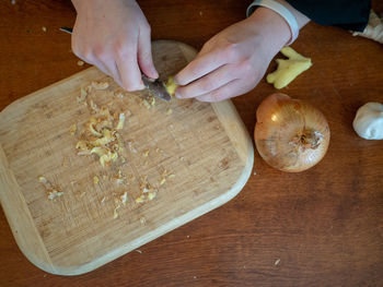 High angle view of hand holding knife on cutting board