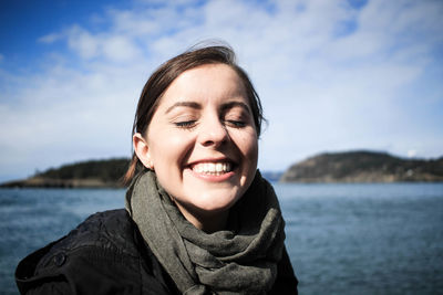 Portrait of smiling young woman against sea