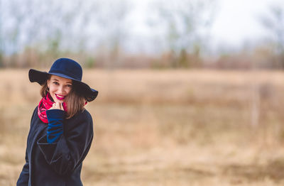 Portrait of smiling woman wearing hat and red scarf against sky