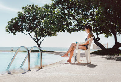 Woman in swimming suit reading a book by the pool.