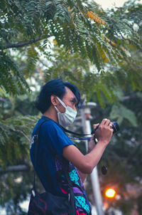 Side view of man photographing against trees