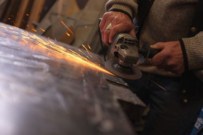 Close-up of man using equipment on metal