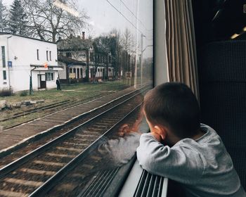 Rear view of man looking through train window