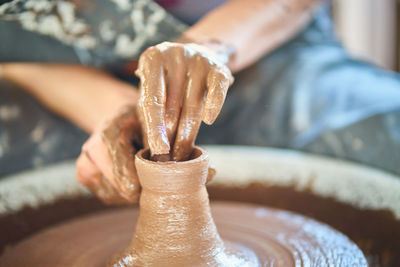 Midsection of person working on pottery wheel