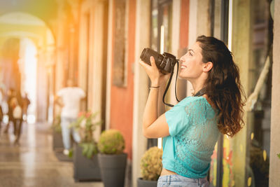 Smiling young woman photographing in city