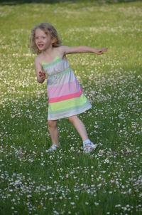 Full length portrait of cute girl standing on grass