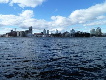 Sea by buildings against sky in city