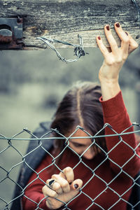 Low section of woman holding chainlink fence