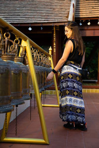 Full length of young woman standing against built structure